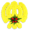 A carefully shaped floral Khanda emblem sits against a clean white backdrop, rendered almost sculpturally from thousands of tightly clustered bright yellow chrysanthemum blooms. The arrangement captures the three essential elements of the Sikh symbol: the central double-edged khanda sword rising true and vertical, the circular chakram formed as a smooth yellow ring, and the two crossed kirpans arcing downwards - each line and curve defined by the dense, sunny petals that give the piece a plush, almost velvety texture. At the heart of the chakram, a compact cluster of five deep red roses is nested amid dark green fern fronds, the glossy foliage folding gently around the rosebuds and heightening their crimson intensity. Soft studio light picks out the chrysanthemum petals' subtle ridges and the roses' layered curves, while a faint grey shadow beneath the tribute anchors it as a physical object - a standing wreath or ceremonial centerpiece. The overall scent would read as a gentle mix of green, sweet rose and a faint chrysanthemum crispness, intended to comfort rather than overwhelm. This floral presentation reads as reverent and carefully considered, suitable for commemorations or cultural gatherings connected to Sikh faith and remembrance. As a Forest Hill visual memory, the piece might be chosen for services near Horniman Museum & Gardens or for community gatherings around Lordship Lane, where neighbours seek a respectful, locally made tribute that balances bold colour with quiet dignity.