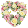 A dense, heart-shaped floral tribute dominates the image, its gentle palette of pinks, creams, and greens evoking tenderness and calm, as though it has just been prepared for a Forest Hill funeral or memorial gathering. The heart is entirely covered with blossoms, creating a thick, plush surface that feels visually soft and embracing. Creamy ivory and subtle lemon-yellow roses serve as the main focal flowers, their rounded, spiralling petals opening in elegant layers that convey poise and devotion. Surrounding and supporting them are clusters of pastel pink carnations, each small bloom with finely ruffled edges that overlap to form a delicate, textured backdrop. Deeper shades of mauve and rose-pink lisianthus punctuate the arrangement, their elegantly flared, cup-shaped petals introducing depth and a quiet, emotional intensity, like a private memory kept close to the heart. Woven through this floral tapestry, stems of silvery-green eucalyptus add a cool touch; their round, slightly matte leaves trace the outline of the heart and rest between blossoms, bringing lightness to the design. Tiny yellow-green buds nestled among the petals offer subtle hints of new life and renewal, balancing the wreath's role as a farewell tribute. The white background ensures that the heart's form and colours are crystal clear, emphasising its meaning as a symbol of love and remembrance. It is easy to imagine this piece being placed at a crematorium near Forest Hill or carried to a quiet service in nearby Dulwich, offering comfort, sympathy, and a gentle, lasting message of care to those who are grieving.