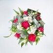 From a top-down view, this lush, rounded bouquet fills the frame against a pure white background, the colours glowing as if lit by soft daylight over Forest Hill. At the heart of the design, generous hot pink carnations with deeply ruffled petals create a frilled, almost cloud-like texture, their intense colour echoed by rich fuchsia roses at varying stages of bloom. Some roses are fully open, spiralling outwards in velvety layers, while tighter buds hint at blossoms still to come, adding a sense of movement and life. Threaded between the bold pinks are clusters of tiny white spray chrysanthemums and other daisy-like flowers, each one forming a neat little mound of crisp petals that brighten the arrangement. Wisps of white gypsophila, or baby's breath, hover delicately among the larger flowers, like a light mist softening the composition. Slender, pale buds reminiscent of white alstroemeria or lily blooms peek up through the canopy, introducing a quiet note of elegance. Around and beneath the flowers, a generous collar of foliage creates structure and depth: silvery-green eucalyptus discs with their satiny, slightly waxy finish mingle with vibrant, narrow leaves that arc outward, while darker, broader leaves are folded and wrapped to form a polished, almost architectural frame. The overall feeling is joyful, generous, and celebratory, like a bouquet ready to be carried along London Road or up from Forest Hill station to mark a birthday, send congratulations, or simply lift someone's spirits at home. The composition suggests the careful hand of an experienced local florist, every stem placed to balance colour, texture, and airiness so the bouquet feels both full and effortlessly fresh.