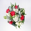 A hand-tied bouquet of red roses, pink-red carnations, white daisies, and wisps of baby's breath rests against a soft, neutral background, glowing as if lit by gentle Forest Hill morning light. The velvety crimson roses form the heart of the arrangement, their petals spiralling tightly in rich, layered folds. Around them, ruffled carnations in vivid raspberry and cherry tones add movement and texture, their edges slightly frilled like festive fabric. Snow-white daisy-style chrysanthemums cluster between the bolder blooms, their golden centres bright and simple, bringing a clean, cheerful freshness that feels like a stroll through nearby Mayow Park on a clear day. Threaded throughout the bouquet, delicate sprays of gypsophila create clouds of tiny white stars, softening every edge and adding a sense of air and celebration. Deep green eucalyptus leaves arc outward, their silvery undertones and rounded shapes lending a modern, almost architectural framing. Behind them, darker tropical greenery provides a lush backdrop, making the whites appear crisper and the reds more saturated. The composition is full but not overwhelming, carefully balanced so each flower is visible and has room to breathe, suggesting the quiet confidence of an experienced local florist. Imagined in the hands of someone welcoming a loved one home in Forest Hill, or placed in a favourite vase on a windowsill overlooking the railway, this bouquet radiates happiness, warmth, and anticipation. It feels perfect for birthdays, congratulations, or simply brightening a corner of the home with the living colour and fragrance of fresh flowers delivered the same day.